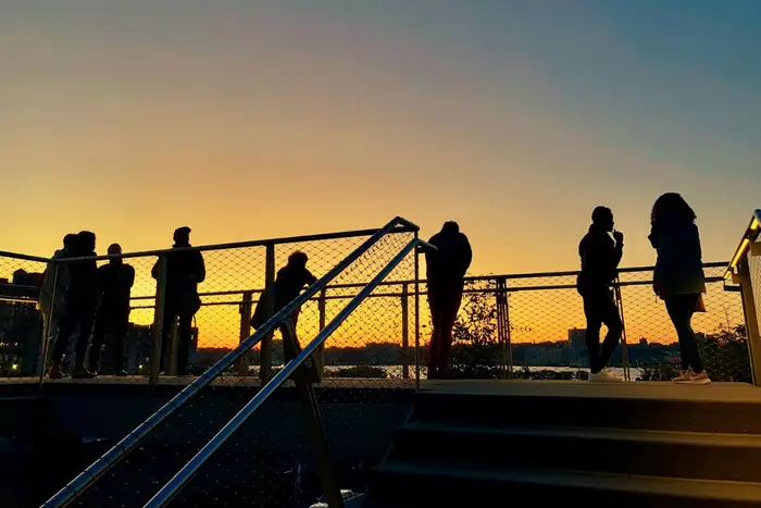 People in Hudson Yards watch the sunset over NJ